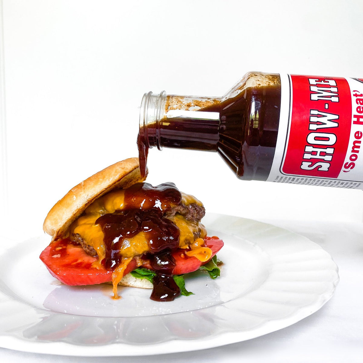 Show-Me® 'Some Heat' Bar-B-Q Sauce being poured over a cheeseburger
