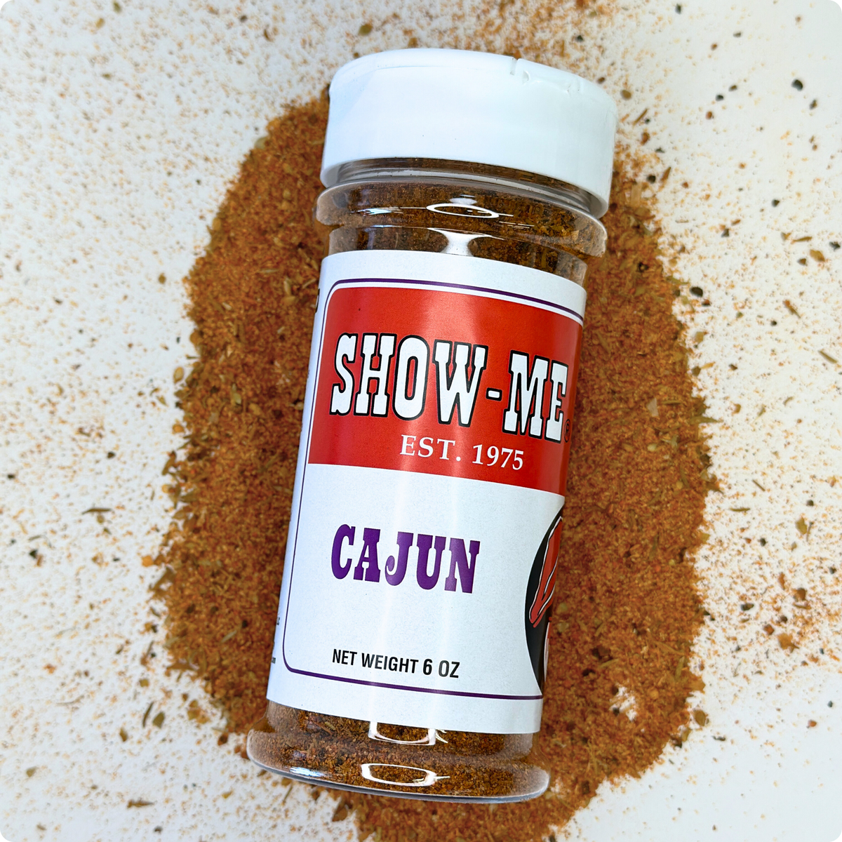 Show-Me® Cajun Seasoning 6 oz shaker lying on a pile of the seasoning blend