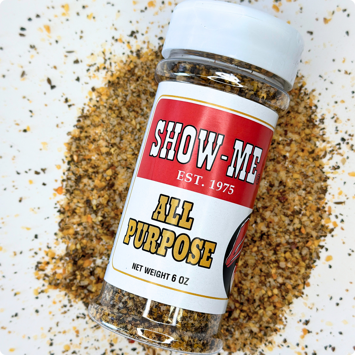 Show-Me® All Purpose Seasoning 6 oz shaker lying on a pile of the seasoning blend